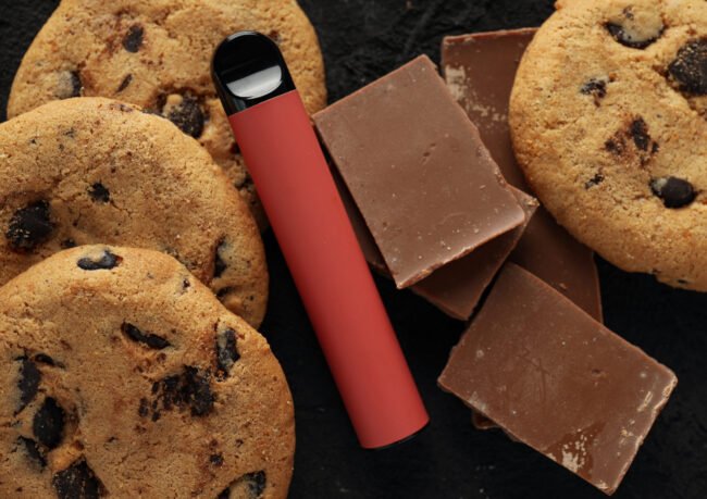 Puff Bar smagsvarianter: Rød e-cigaret med chokolade og cookies på mørk baggrund